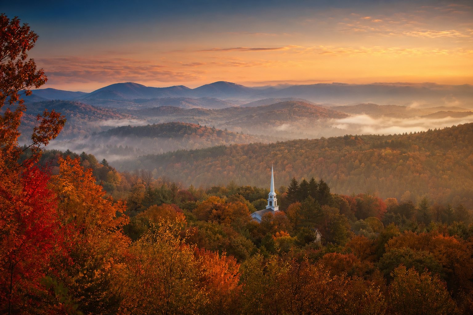 Modern photograph of the Green Mountains in autumn with a New England steeple representing Credo Enterprise' Vermont service area
